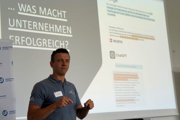 Mann spricht auf einer Veranstaltung über Unternehmensstrategie und Erfolg.